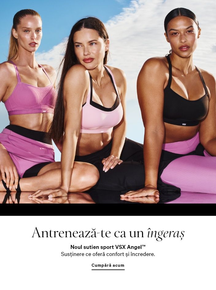 Femeie purtând un set de pijama alb, cu cămașă și pantaloni scurți, stând într-un cadru de ușă.