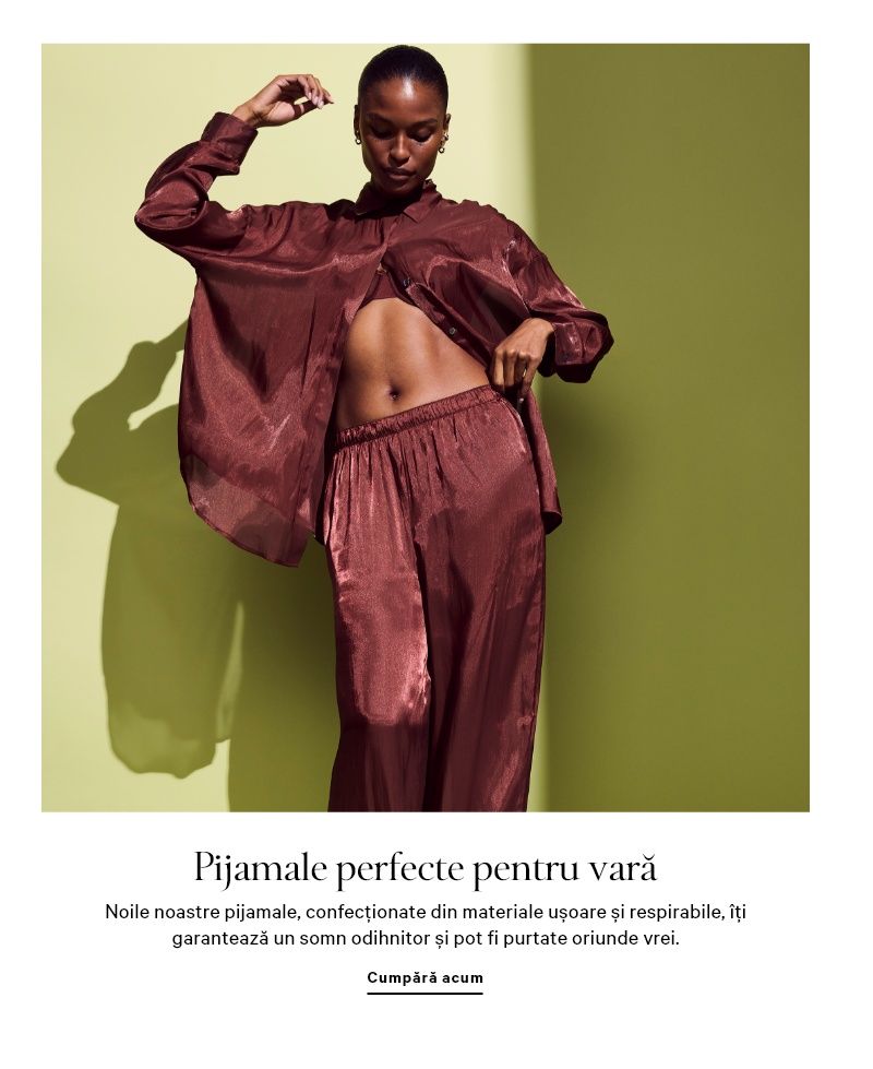 Femeie purtând un set de pijama alb, cu cămașă și pantaloni scurți, stând într-un cadru de ușă.