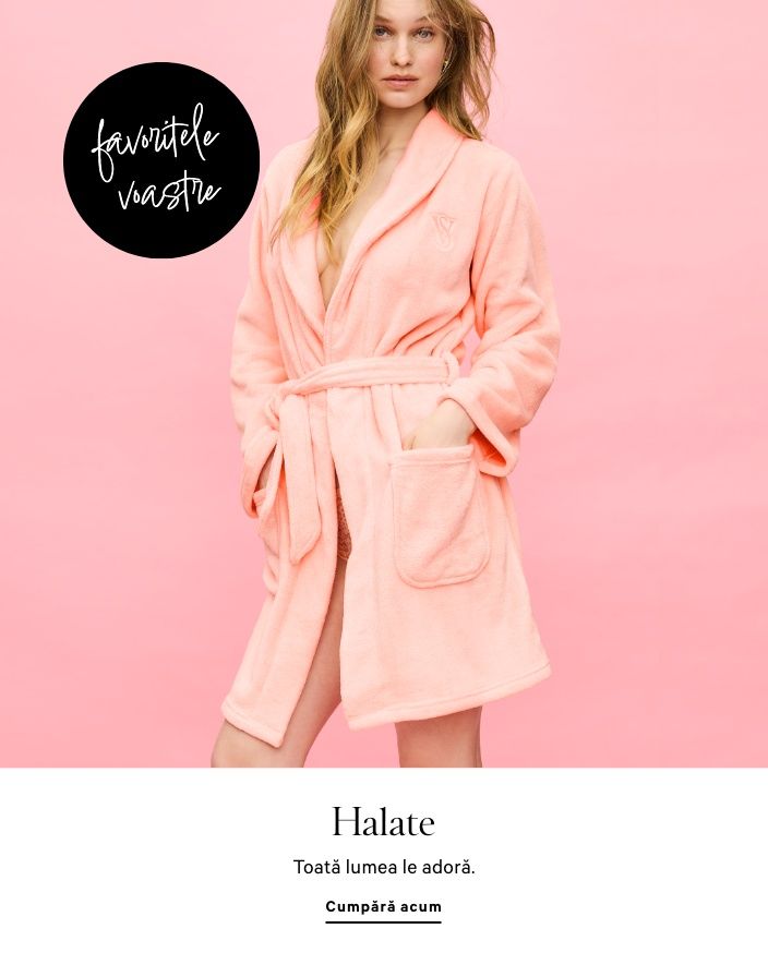 Femeie purtând un set de pijama alb, cu cămașă și pantaloni scurți, stând într-un cadru de ușă.