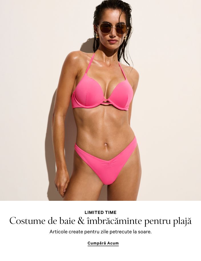 Femeie purtând un set de pijama alb, cu cămașă și pantaloni scurți, stând într-un cadru de ușă.