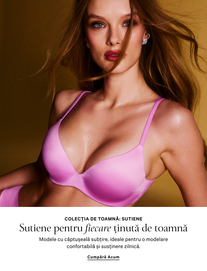 Femeie purtând un set de pijama alb, cu cămașă și pantaloni scurți, stând într-un cadru de ușă.